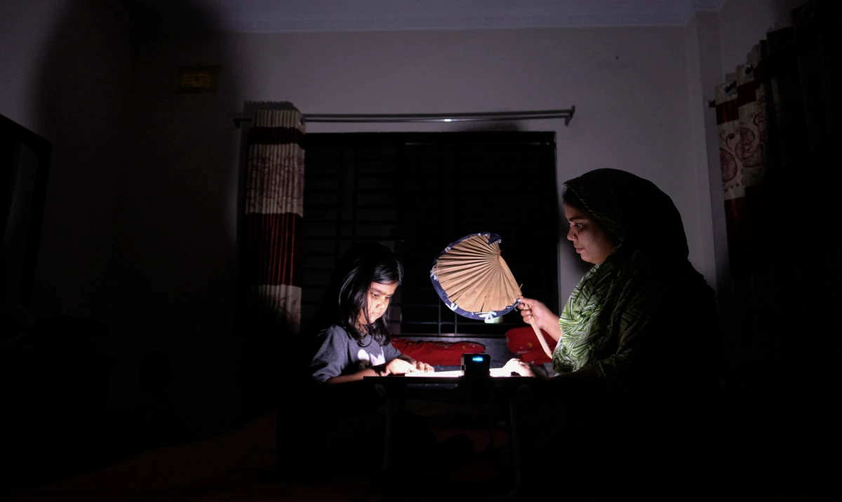 A Bangladeshi woman uses a traditional hand fan as she assists her daughter in her studies during a power cut at their home in Pilkhana area, Dhaka, Bangladesh, Tuesday, Aug.23, 2022. (AP)