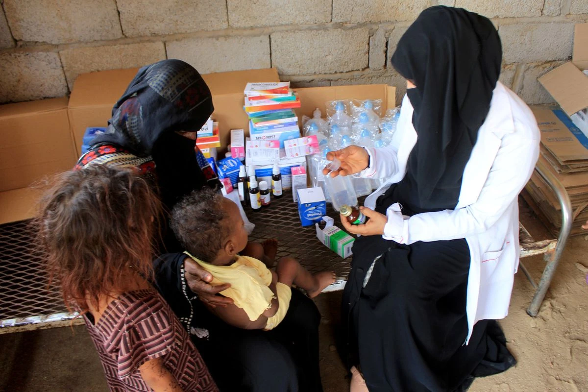 Volunteer health worker Ashwaq Mahmoud checks a medicine as she helps a child in Abs, Yemen September 13, 2021. (Reuters)