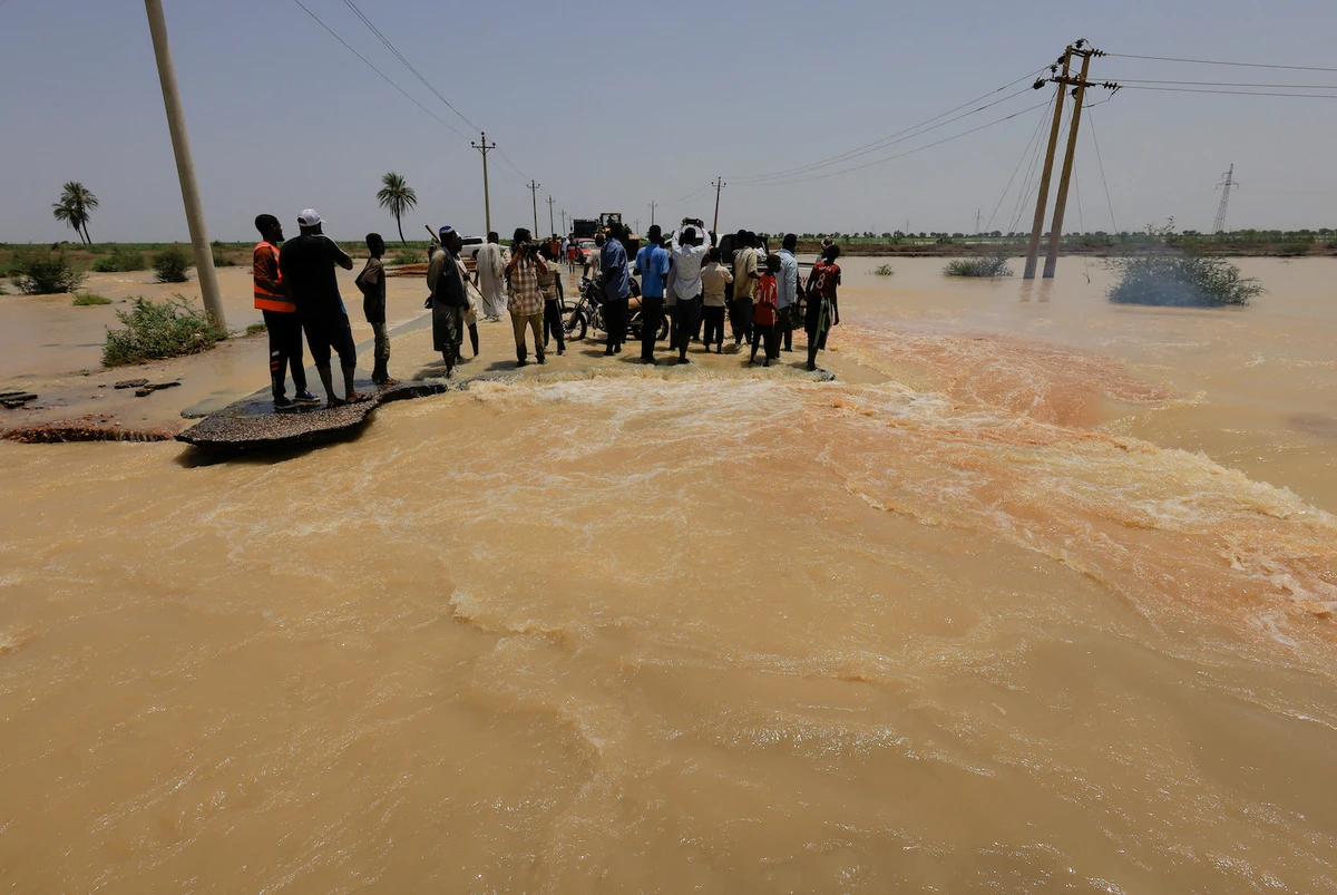People stand amidst the floodwaters in Al-Managil locality in Gezira state, Sudan, August 23, 2022. (Reuters)