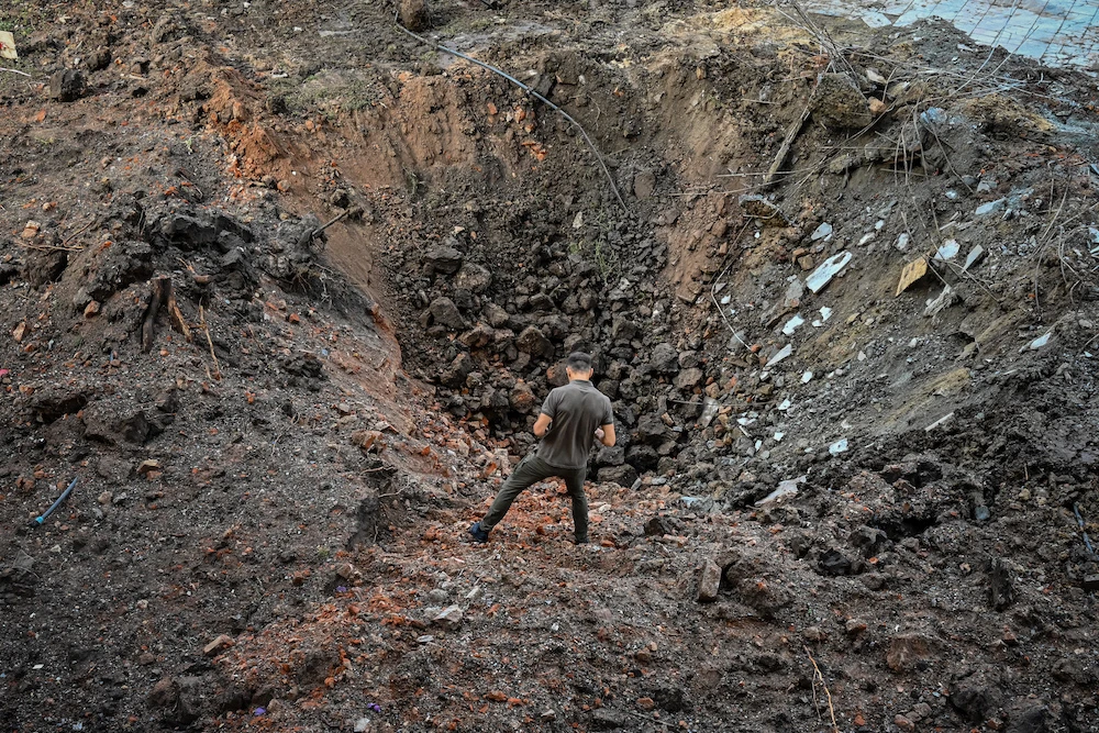 A Ukrainian military personnel stands beside a crater near the damaged headquarters of the Kharkiv administration building following an overnight missile strike in Kharkiv. (AFP)
