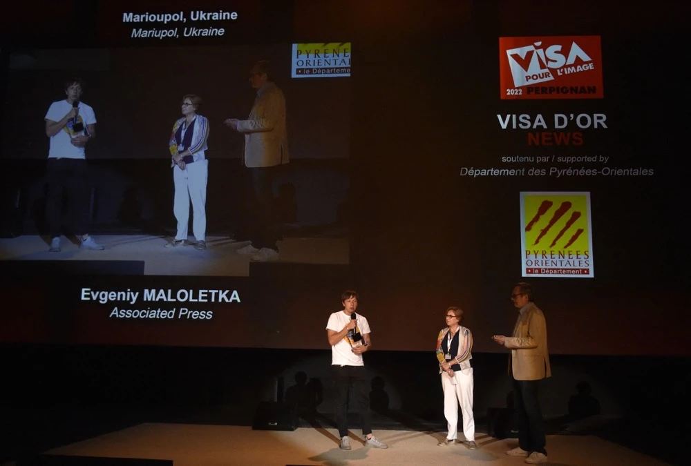 Ukrainian photographer Evgeniy Maloletka (L) receives the Visa d'or News award during the 34th edition of Visa pour l'Image international photojournalism festival in Perpignan, southern France on September 3, 2022. (AFP)