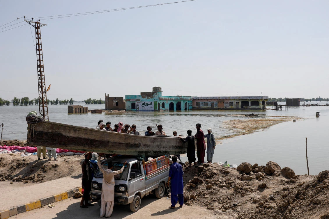 People launch a wooden boat in to rising flood waters on the indus highwat, following rains and floods during the monsoon season in Mehar, Pakistan. (Reuters)