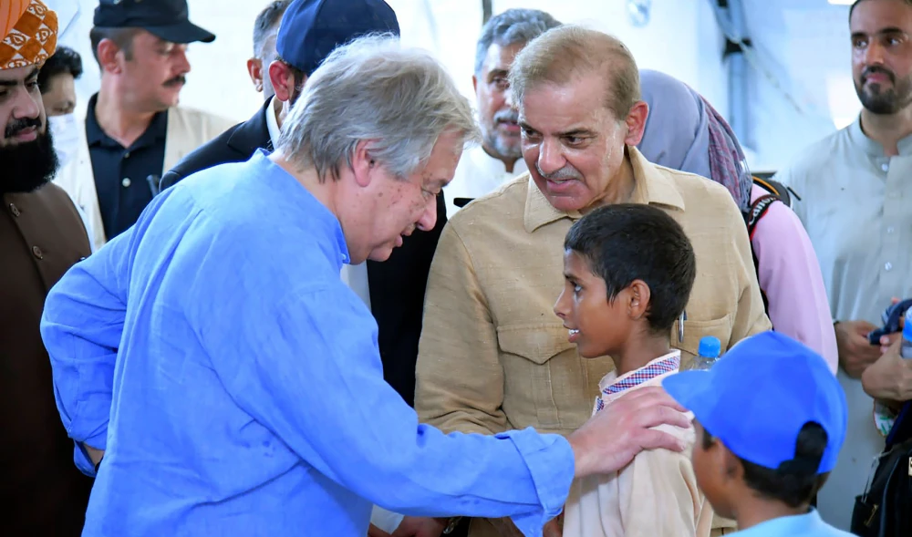 Prime Minister Shahbaz Sharif, center right, and U.N. Secretary-General Antonio Guterres, left, interact with children at a school set up at a flood relief camp in Jaffarabad, Pakistan, Saturday, Sept. 10, 2022. (AP)
