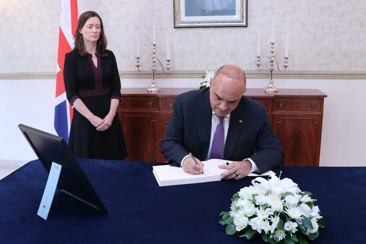 Jordanian PM Bisher Al-Khasawneh writes in a condolence book at the British embassy in Amman after the passing of Queen Elizabeth II. (Jordan News Agency)