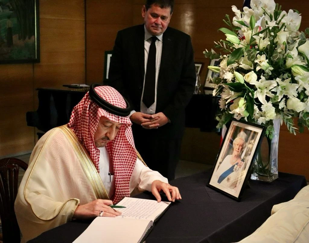 Saudi Arabia’s Deputy FM Waleed Al-Khuraiji writes a message in the condolence books while accompanied by the UK’s ambassador to the Kingdom. (SPA)