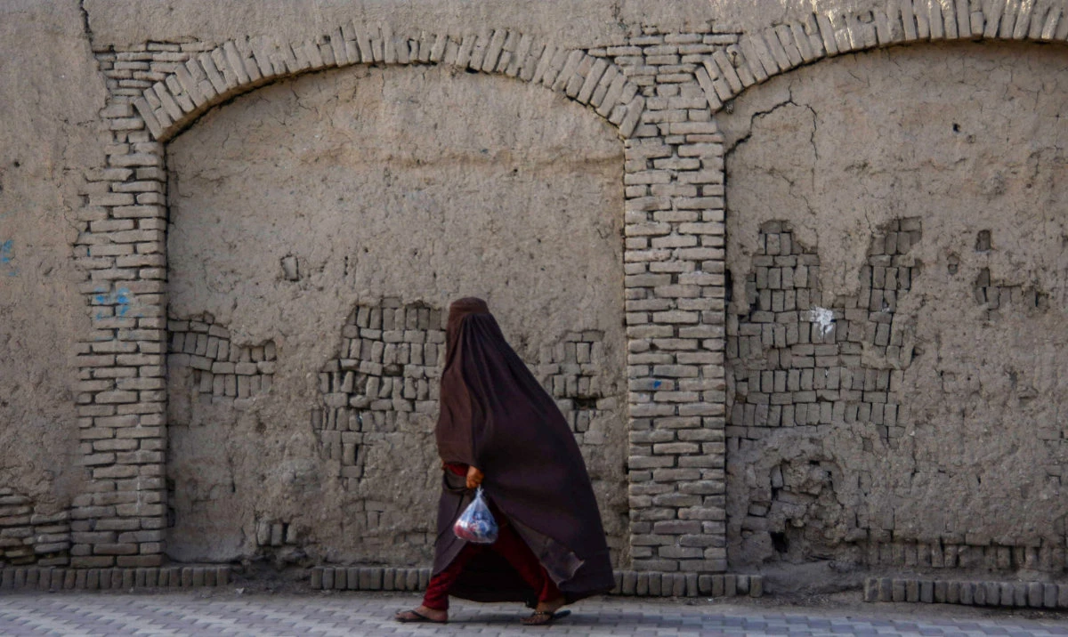 An Afghan woman walks past a boundary wall along a road in Kandahar on September 12, 2022. (AFP)