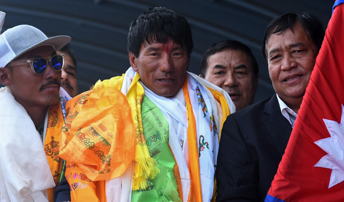 Nepali mountaineer Sanu Sherpa (C) is welcomed upon arriving at Tribhuvan airport after becoming the first climber to summit all the world's 14 peaks above 8000 meters (26,247 ft) for the second time, in Kathmandu on August 20, 2022. (AFP)