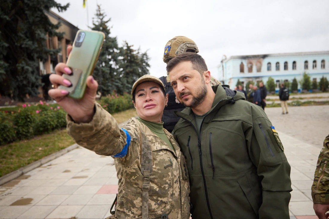 Ukrainian President Volodymyr Zelensky (C) poses for a selfie with a servicewoman in the de-occupied city of Izyum, Kharkiv region. (AFP)