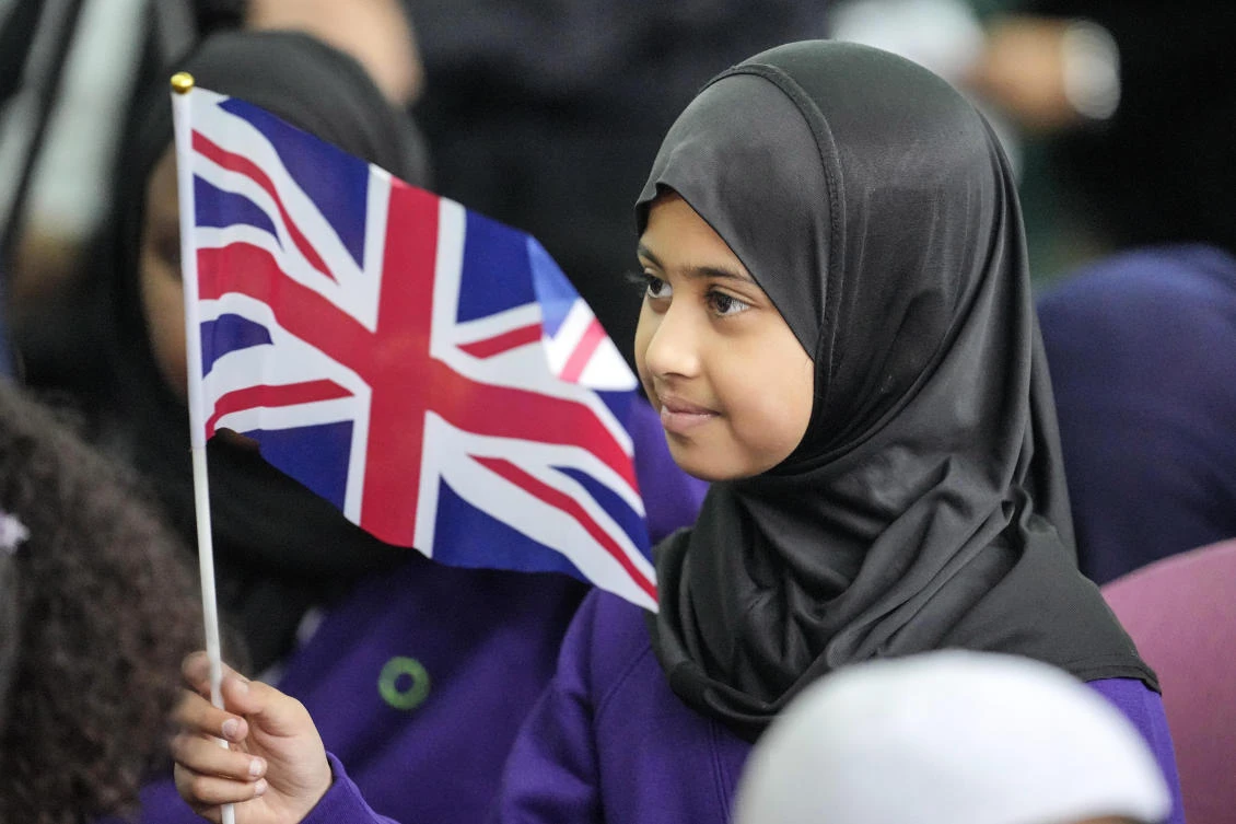 A girl from the Olive School waves a Union Jack flag during a national Muslim memorial for the late Queen Elizabeth II at the London Central Mosque on Sept. 15, 2022. (AP)