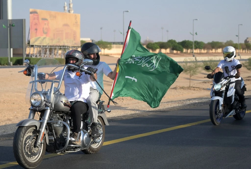Saudi and expat members of the Hawks Riyadh MC club wave a Saudi flag as they ride their motorcycles around Riyadh during a parade to mark Saudi National Day. (File/AFP)