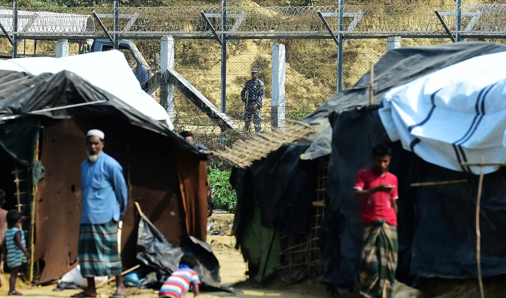 A Myanmar security personnel keeps watch along the Myanmar-Bangladesh border as Rohingya refugee stand outside their makeshifts shelters in Bandarban, Bangladesh. (AFP file photo)