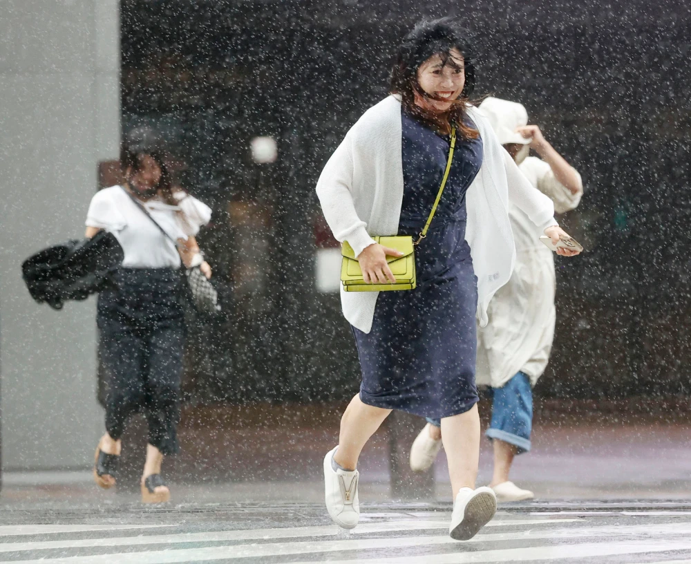 People make their way through the strong wind and rain in Kagoshima, southern Japan, Sunday, Sept. 18, 2022, as a powerful typhoon pounded southern Japan. (AP)