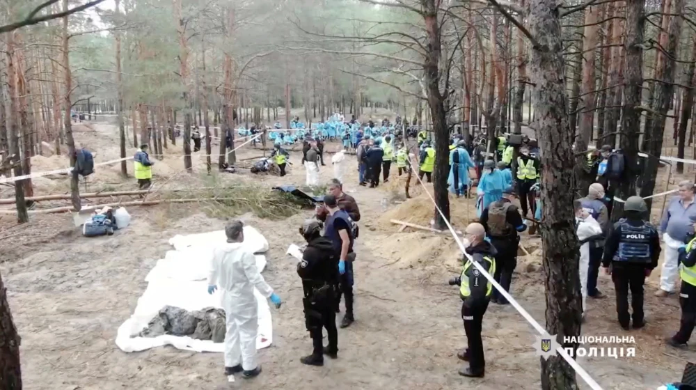 Forensic personnel work at a mass burial site near the town of Izium, Ukraine, in this screen grab obtained from a video released September 20, 2022. (REUTERS)
