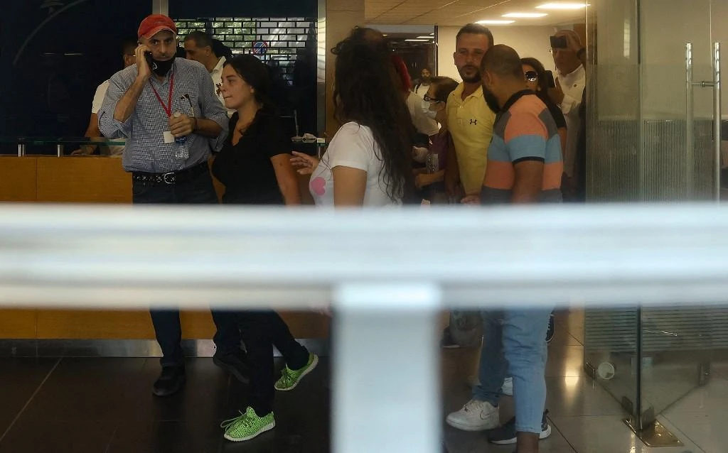 Sali Hafiz, in green shoes, held up a Beirut branch of BLOM Bank last week, taking by force some $13,000 in savings in her sister’s account frozen by capital controls. (AFP)