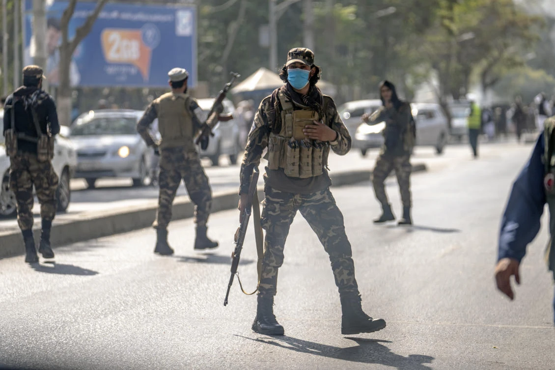 Taliban fighters stand guard at the explosion site, near a mosque, in Kabul on Friday and police confirmed casualties. (AP)
