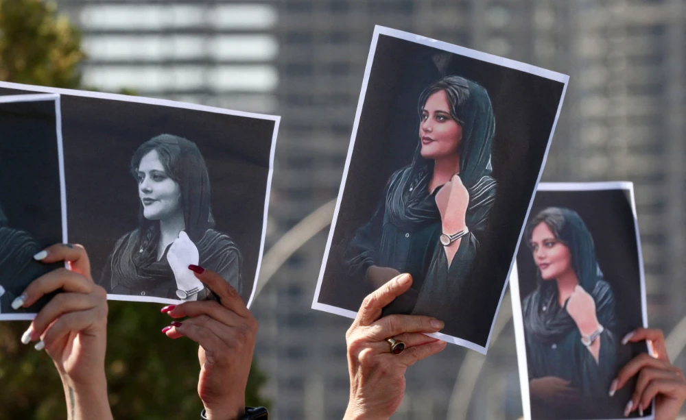 Women hold up signs depicting te image of 22-year-old Mahsa Amini, who died while in the custody of Iranian authorities, during a demonstration denouncing her death outside the UN offices in Arbil on September 24, 2022. (AFP)