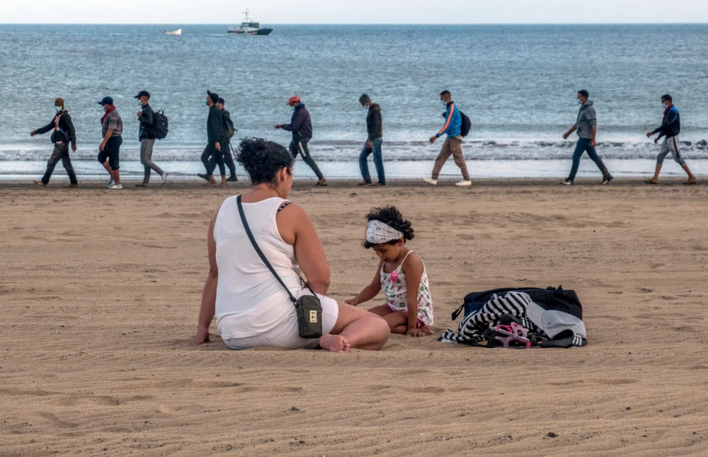 Migrants from Morocco walk along the shore escorted by Spanish Police after arriving at the coast of the Canary Island, crossing the Atlantic Ocean sailing on a wooden boat on Oct.20, 2020. (AP)