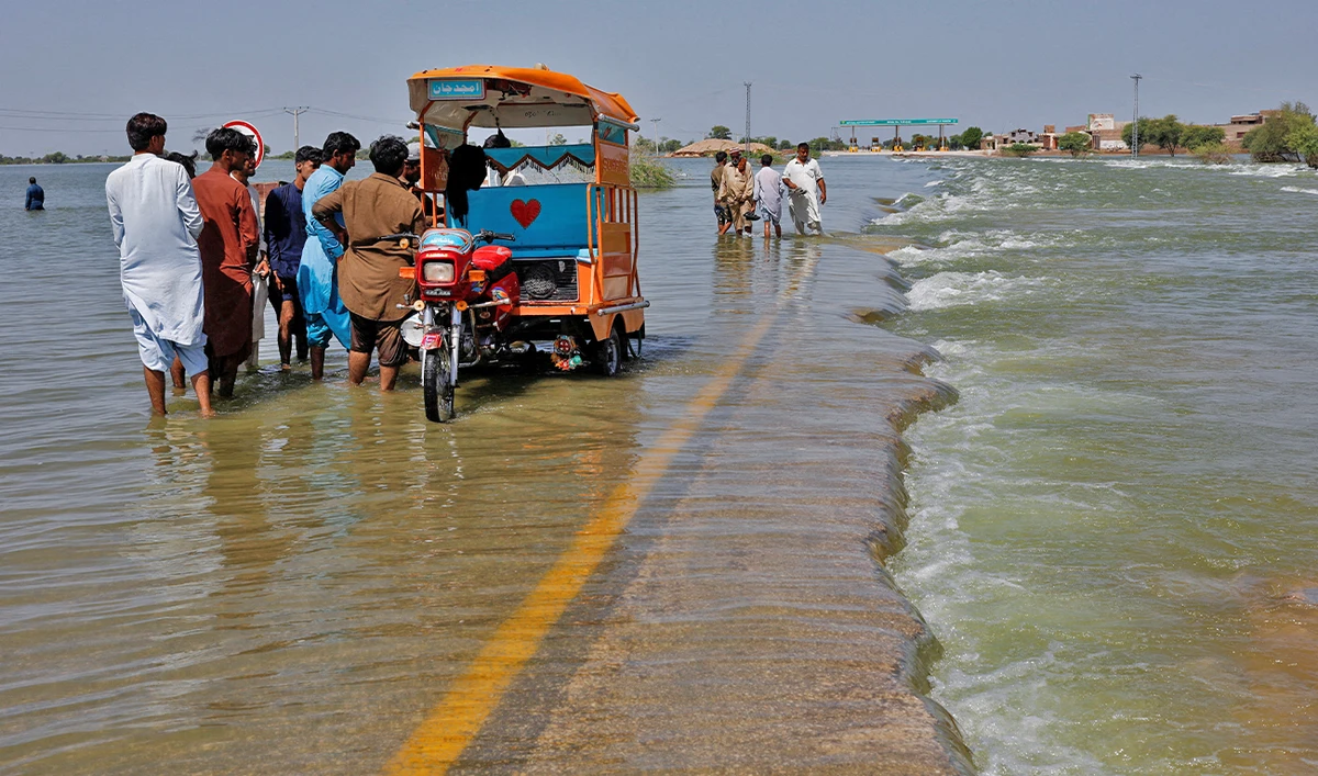Displaced people stand on flooded highway, following rains and floods during the monsoon season in Sehwan, Pakistan, on September 16, 2022. (REUTERS)
