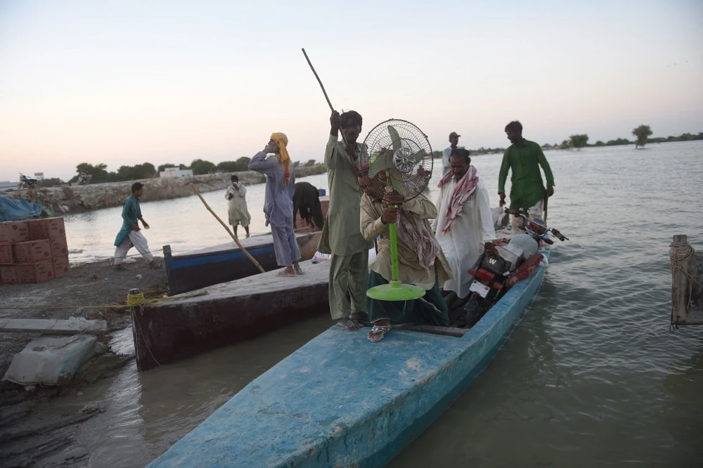 Internally displaced people use a boat to cross the flooded area in Dadu district, Sindh province. (AFP)