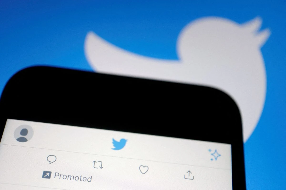 A promoted tweet on Twitter app is displayed on a mobile phone near a Twitter logo, in this illustration picture taken Sept. 8, 2022 (REUTERS)