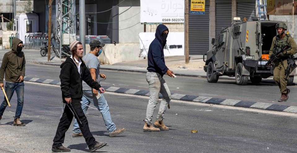Israeli settlers, wielding batons, attack Palestinian residents and shops, Huwara, occupied West Bank, Oct. 13, 2022. (AFP)