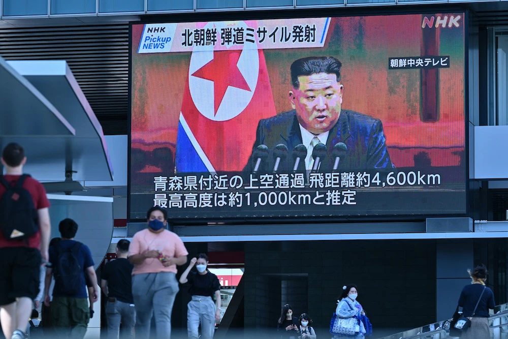 Pedestrians walk under a large video screen showing images of North Korea's leader Kim Jong Un during a news update in Tokyo on October 4, 2022, after North Korea launched a missile. (AFP)