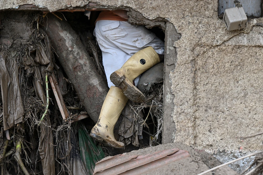 A resident searches for his missing relatives in the rubble of a house destroyed by a landslide during heavy rains in Las Tejerias, Aragua state, Venezuela. (AFP)
