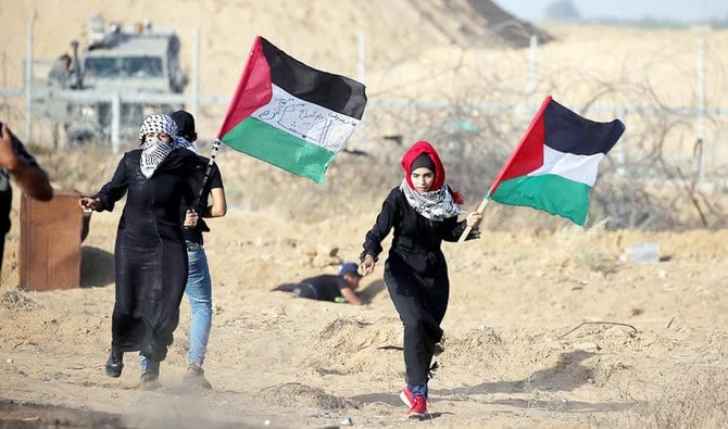 Women holding Palestinian flags run for cover from Israeli gunfire and tear gas during a protest in Gaza. (Reuters/File)