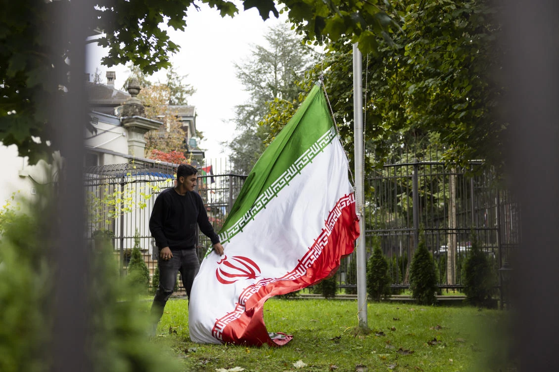 A protester hauls down the Iranian flag in the grounds of the Iranian embassy in Bern, Switzerland, Saturday, Oct. 1, 2022. (AP Photo)