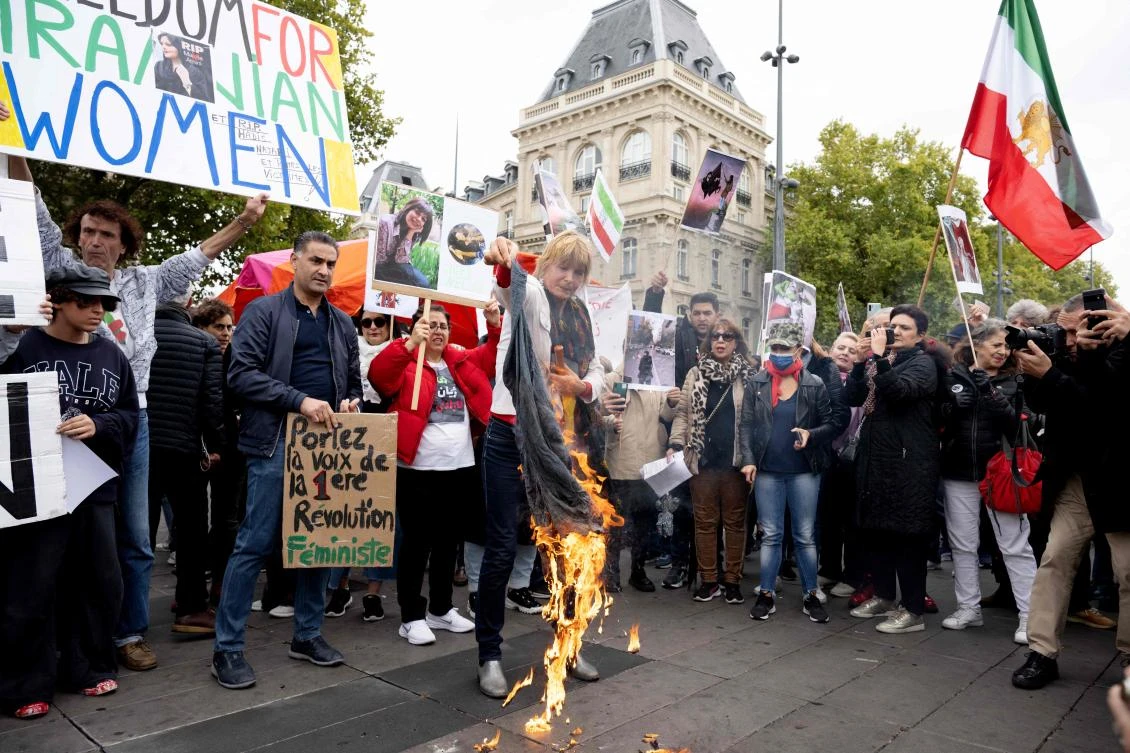 A woman burn headscarves in support of Mahsa Amini during a protest on Place de la Republique in Paris. (AFP)