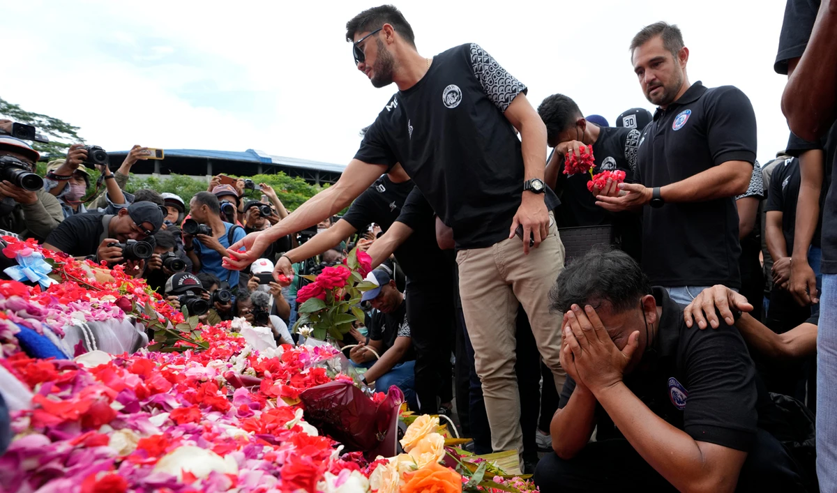 Players and officials of the soccer club Arema FC pray outside Kanjuruhan Stadium where riots broke out on Saturday night, in Malang, Indonesia, October 3, 2022. (AP)