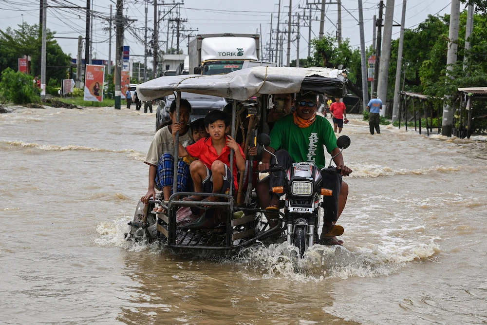 Residents and motorists commute along a flooded highway in the aftermath of Super Typhoon Noru in San Ildefonso, Bulacan province on September 26, 2022. (AFP)