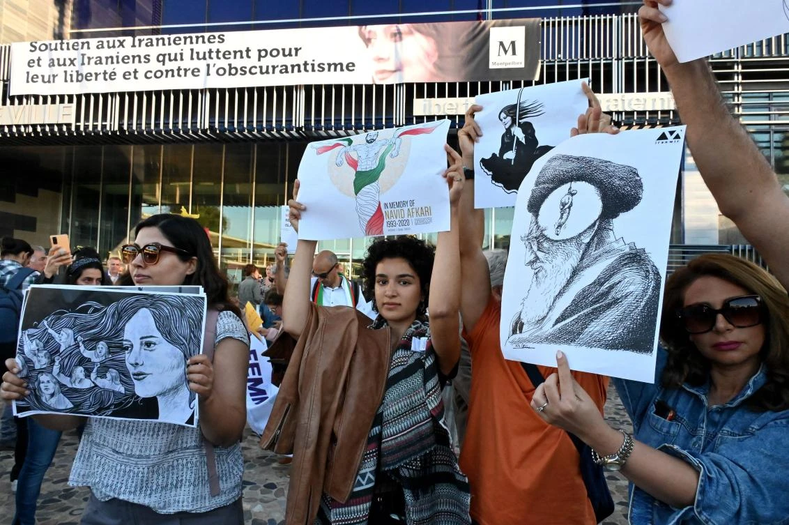 Women protest with placards during the unveiling of a banner on the facade of the town hall in support of the Iranians fighting for their freedom and against obscurantism in their country, in Montpellier, France, on October 3, 2022. (AFP)