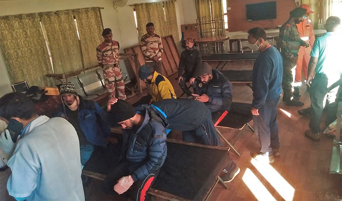 Evacuees (L) rest after receiving first aid at the ITBP Matli helipad station on October 5, 2022, after being airlifted during a rescue operation for 26 missing climbers struck by an avalanche in the northern state of Uttarakhand. (AFP)