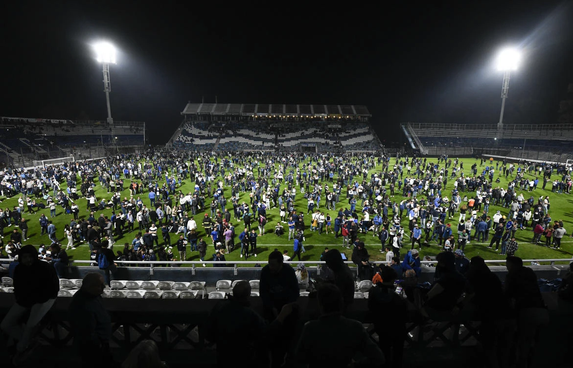 Fans of Gimnasia de La Plata take to the pitch after tear gas flooded the stadium during a local tournament soccer match between Gimnasia de La Plata and Boca Juniors in La Plata, Argentina on Thursday. (AP)