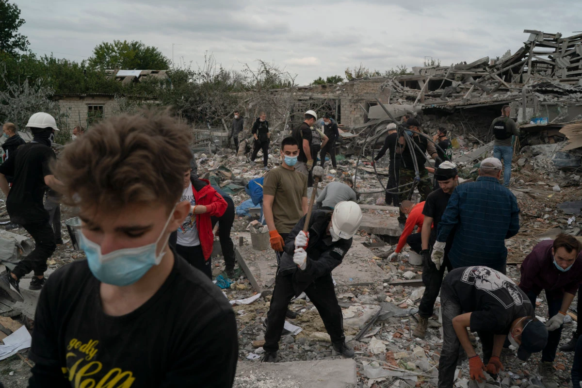 Volunteers work to clean the debris on a site where several houses were destroyed after a Russian attack at a residential area in Zaporizhzhia, Ukraine, on Oct. 9, 2022. (AP Photo/Leo Correa)