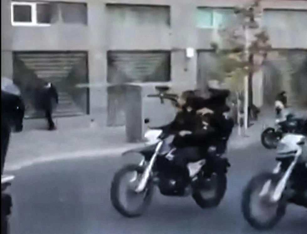 This grab taken from a UGC video posted on Septembre 21, 2022, shows what appears to be Iranian security forces driving motorcycles and firing at protesters in Tehran's Valiasr square. (AFP)