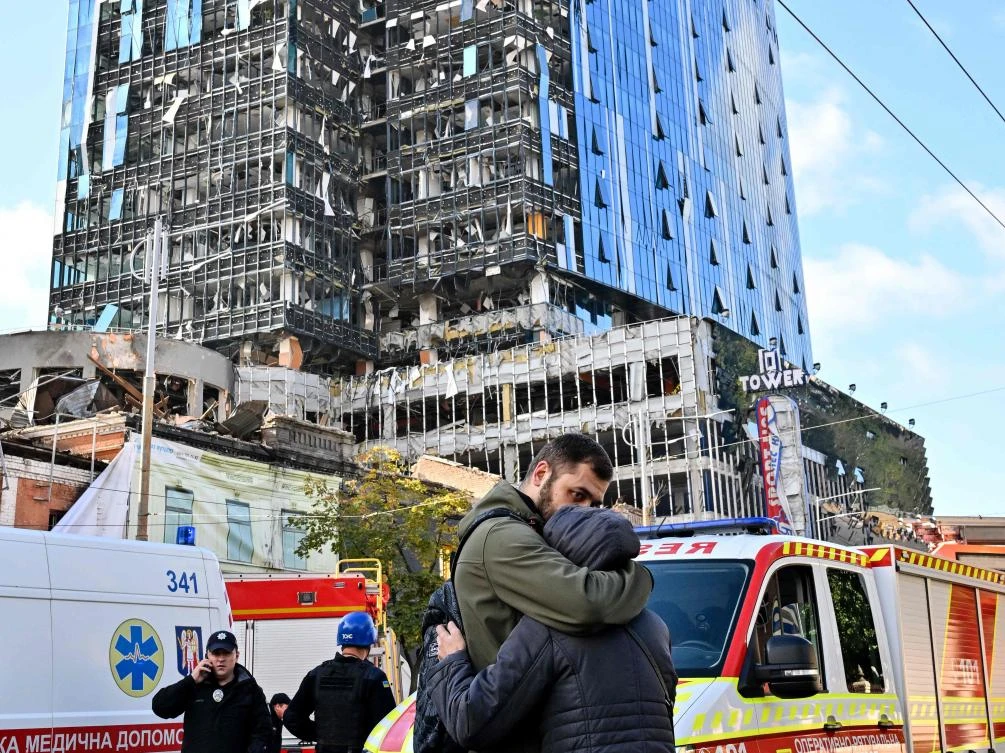 People react outside a partially destroyed multistory office building after several Russian strikes hit the Ukrainian capital of Kyiv on October 10, 2022, amid Russia’s invasion of Ukraine. (AFP)