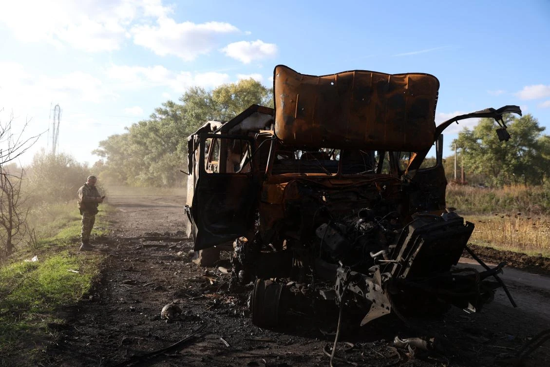 A Ukrainian serviceman stands next to a destroyed Russian military truck in eastern Ukraine. (AFP)