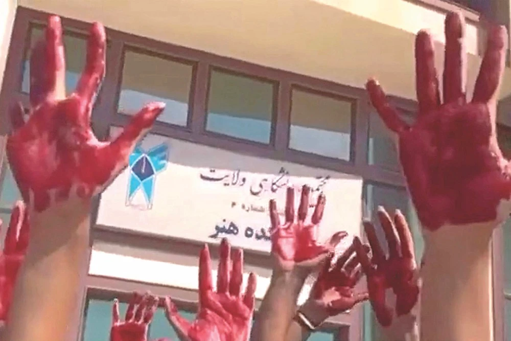 Students of Tehran’s Azad University protest with their palms covered in red paint to symbolize the blood of slain demonstrators. (AFP)