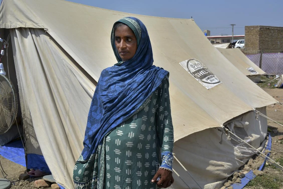 Shakeela Bibi who is pregnant stands beside her tent at a relief camp for flood victims, in Fazilpur near Multan, Pakistan, Sept. 23, 2022. (AP Photo/Shazia Bhatti)