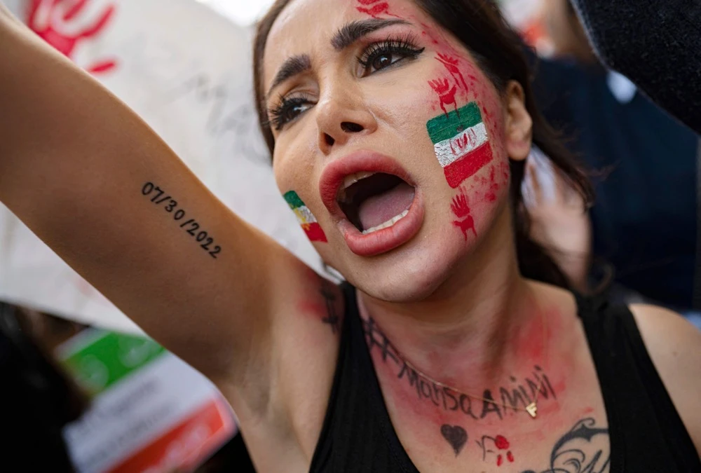 A demonstrator with an Iranian flag painted on her face, shouts slogans as she participates in a rally outside the Iranian consulate in Istanbul on October 17, 2022. (AFP)
