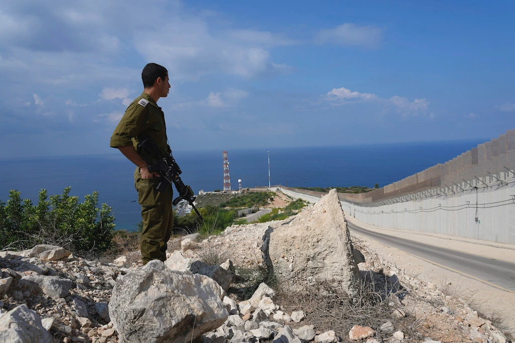 An Israeli soldier stands near the fence on the Israeli border with Lebanon in Ras Hanikra , Friday, Oct. 14, 2022. (Reuters)