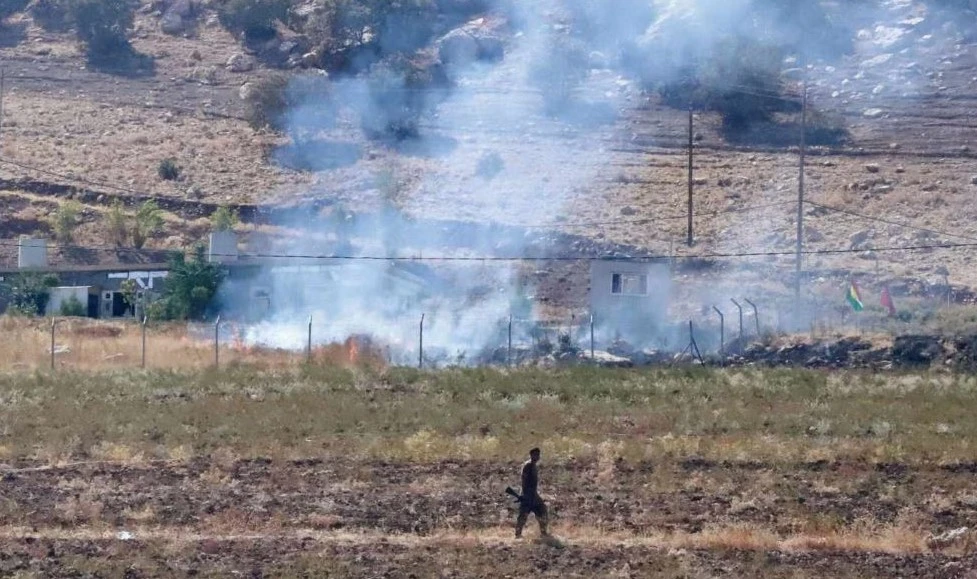 A Kurdish peshmerga fighter walks as smoke billows in the area of Zargwez, outside the Iraqi city of Sulaimaniyah, where several exiled Iranian Kurdish parties maintain offices, Sept. 28, 2022. (AFP)