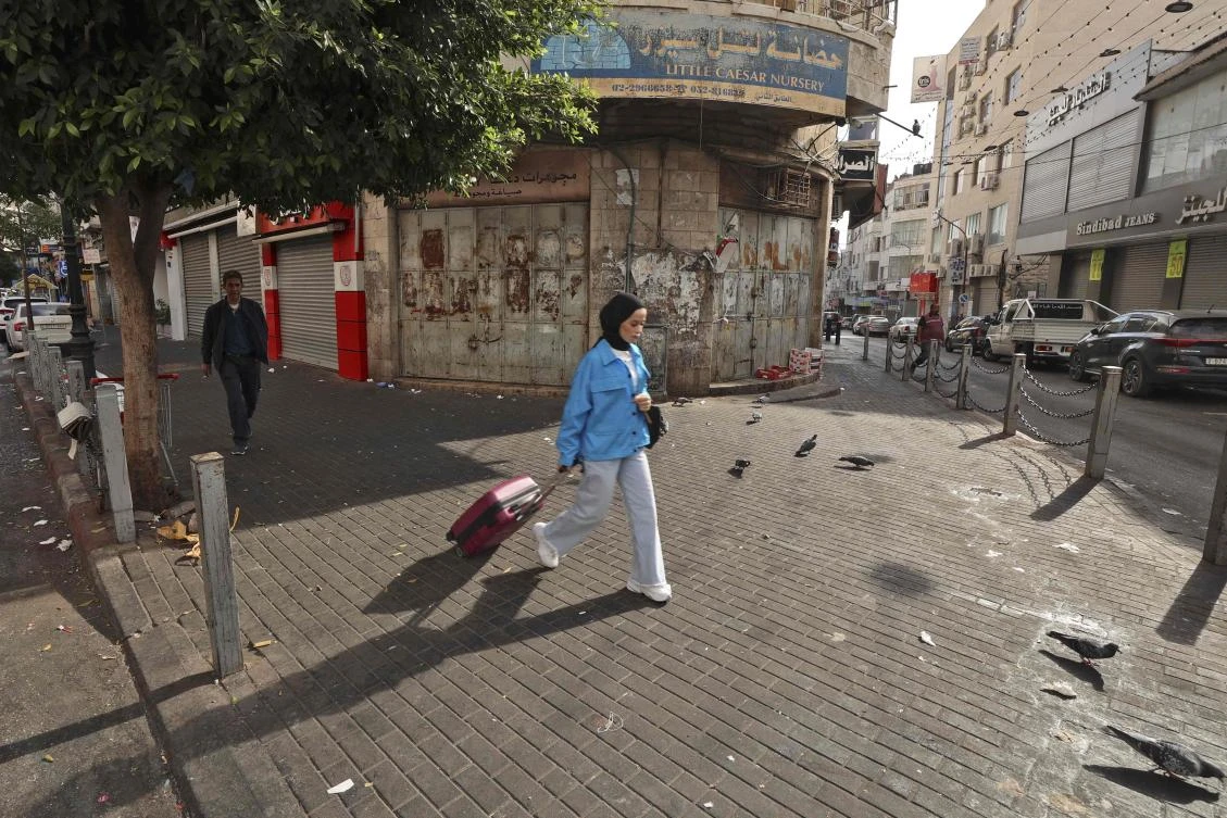 Palestinians walk in an empty street in Ramallah in the occupied West Bank on Oct. 20, 2022 during a general strike in protest of the killing of Palestinian fugitive. (AFP)