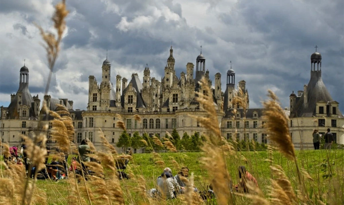 People sit on the grass in front of the Chateau of Chambord in Chambord, central France. (AFP/File)