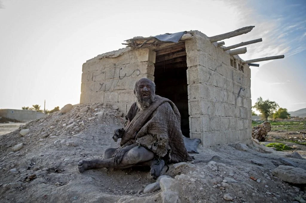 In this file photo taken on December 28, 2018 Amou Haji (uncle Haji) sits in front of an open brick shack that the villagers constructed for him. (AFP/File)