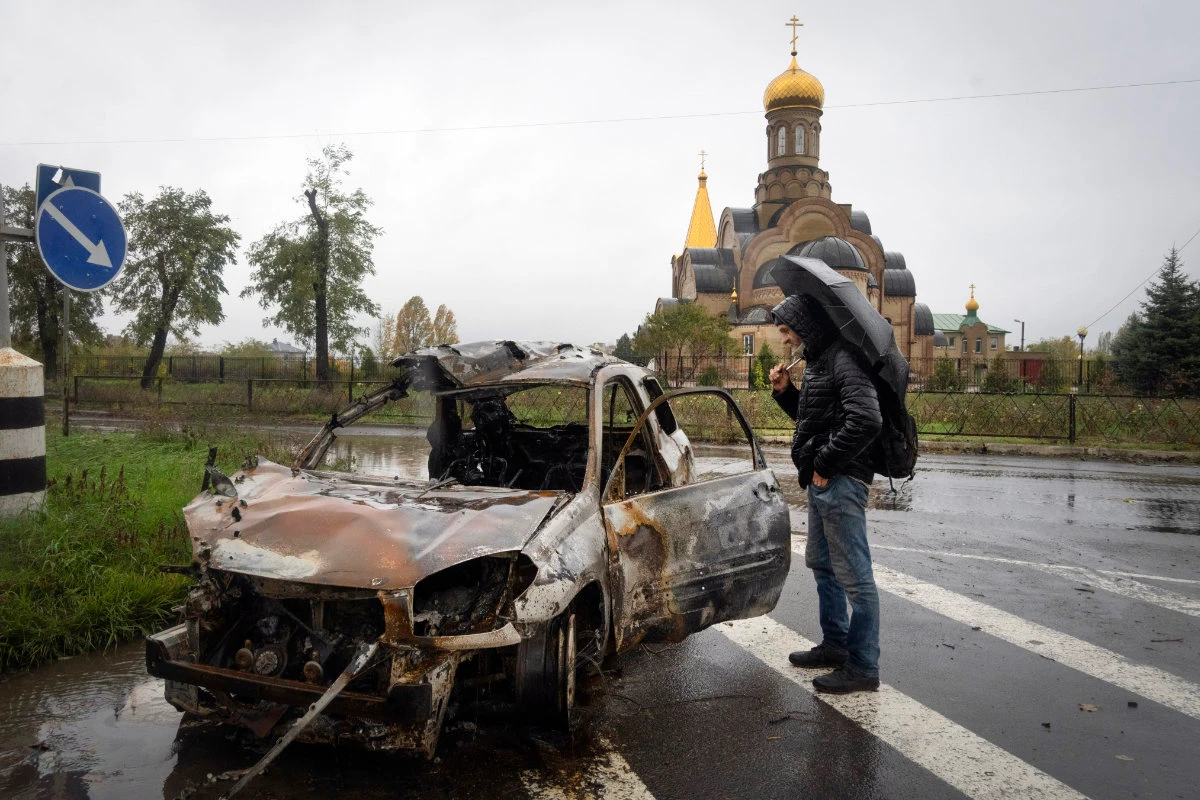 A passerby looks at a car damaged by Russian shelling in central Bakhmut, the site of the heaviest battle in Ukraine's Donetsk region on Oct. 26, 2022. (AP Photo/Efrem Lukatsky)