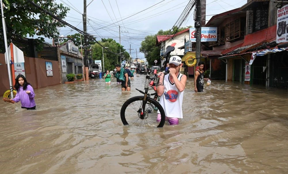 Residents wade through a flooded street in Kawit town, Cavite province on October 30, 2022, a day after Tropical Storm Nalgae hit. (AFP)