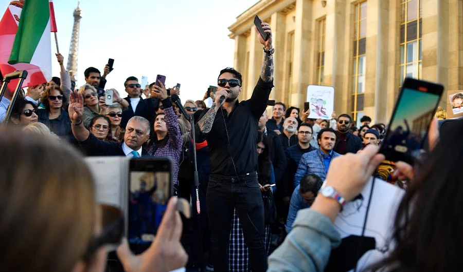 An Iranian rapper performs during a rally in support of Iranian protests in Paris, with the Eiffel Tower in the background, on October 9, 2022. (AFP)